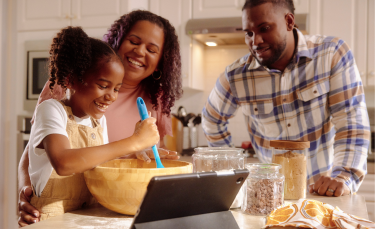 A father and mother both are doing some fun while making the food with his child.